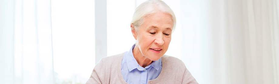 Smiling older woman looking down at research on annuity benefits