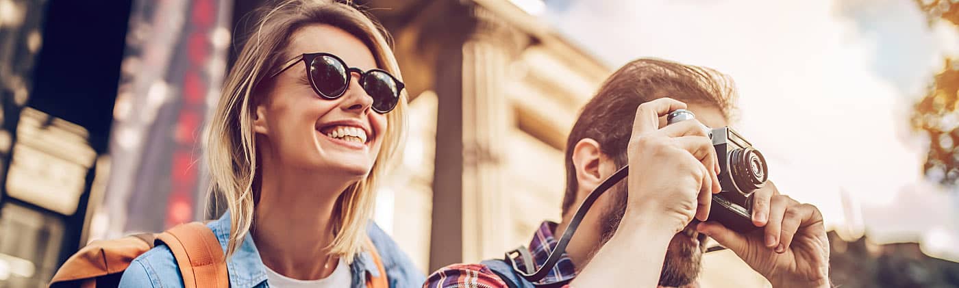 Tourist couple smiling and taking pictures after reading tips for traveling abroad 