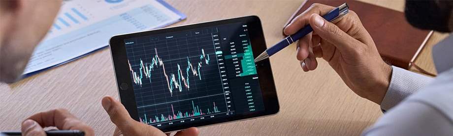 Two individuals review how stocks work while looking at a chart using a mobile device.