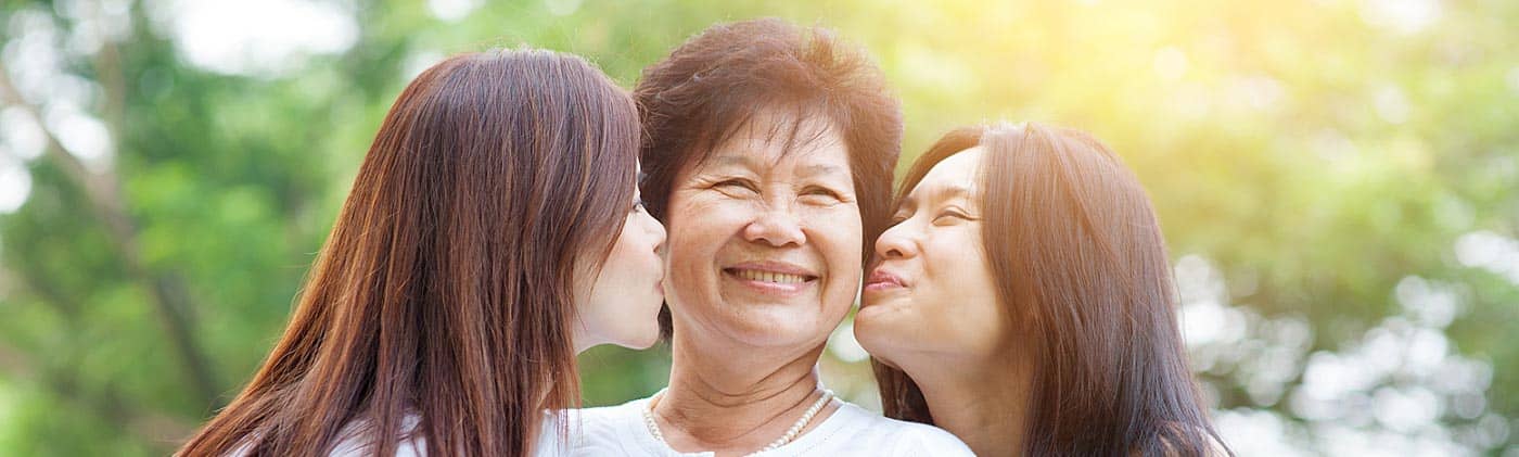 Two daughters kiss their mother on the cheek: buying life insurance