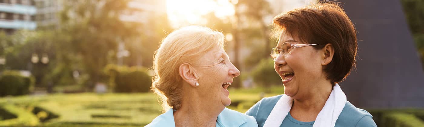 Two elderly women looking at each other smiling and talking about age-related cognitive decline 