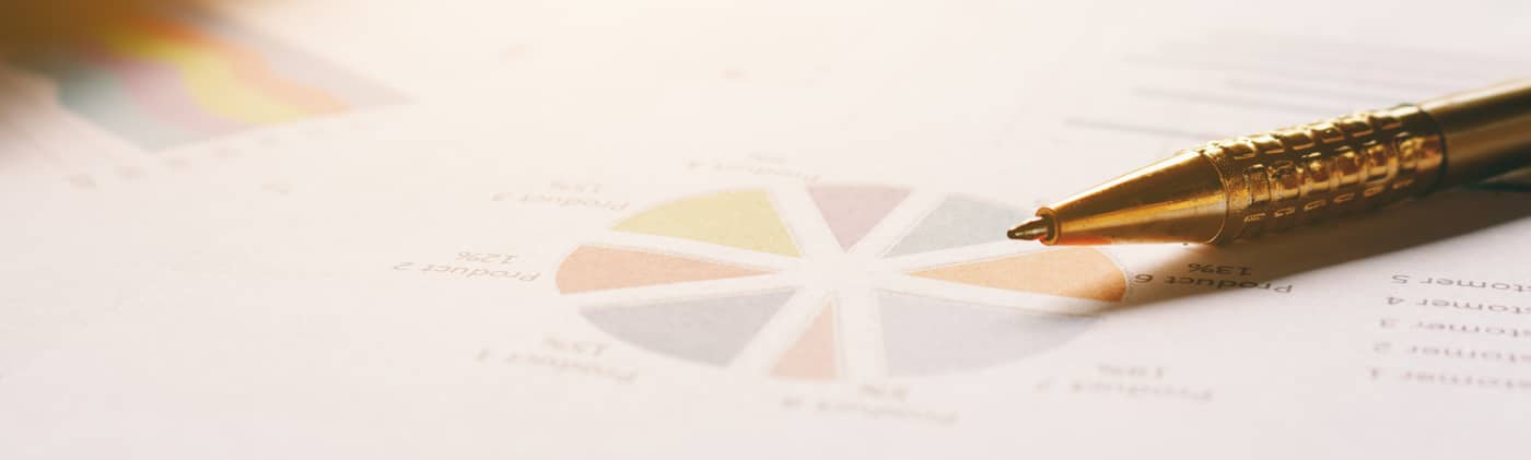 gold pen on paper with charts