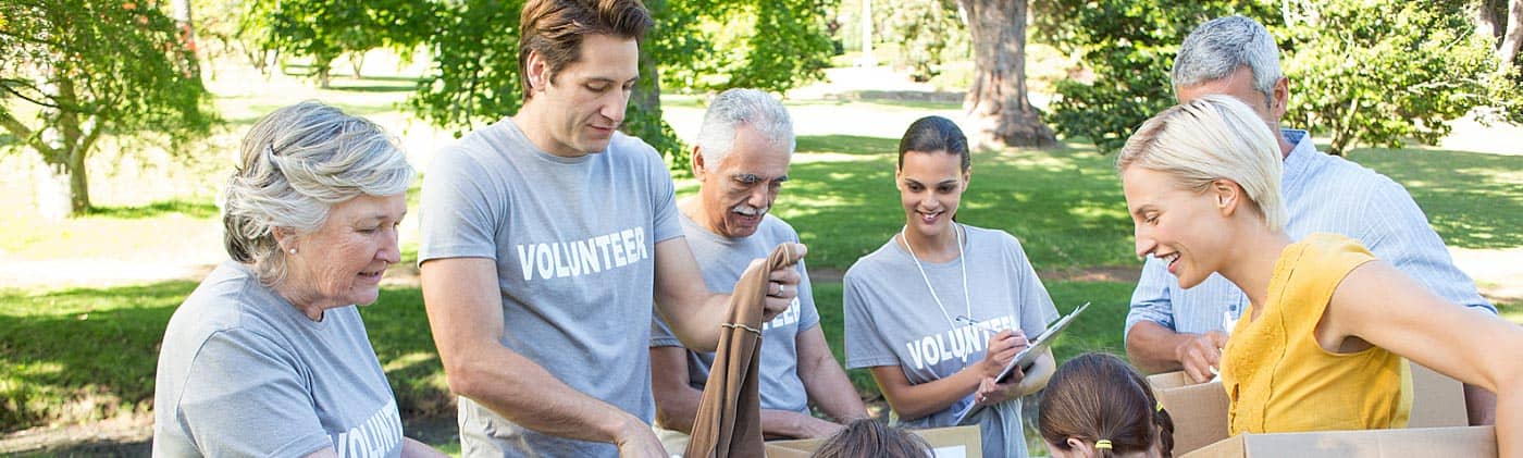 volunteers take donations on a sunny day in a park and discuss financial advantages of a charitable trust
