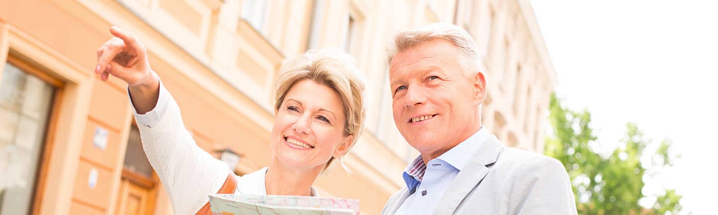 Smiling older couple wondering when to retire look at a map