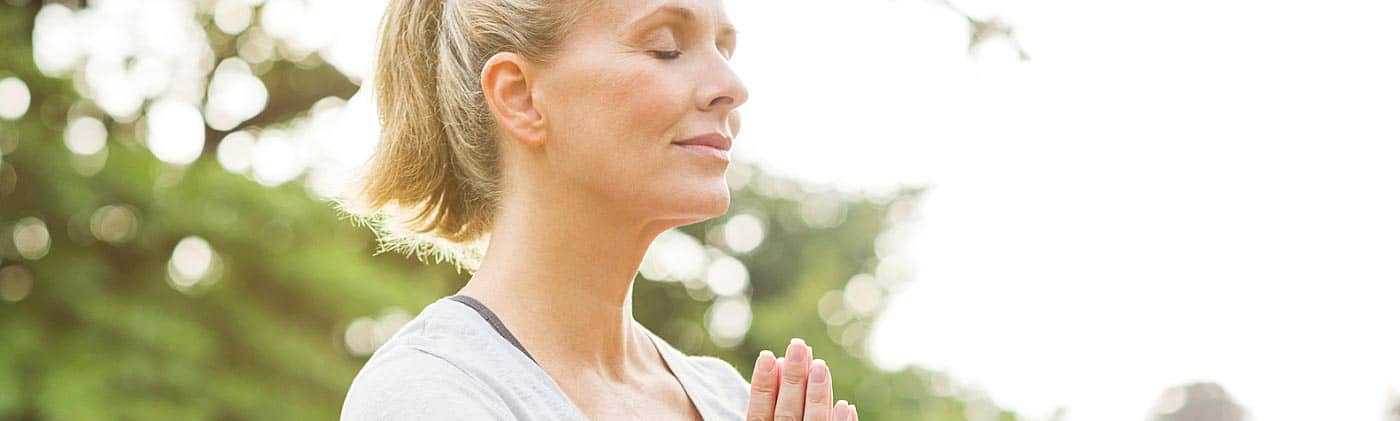 Woman in a meditative yoga pose in a park: stress reduction