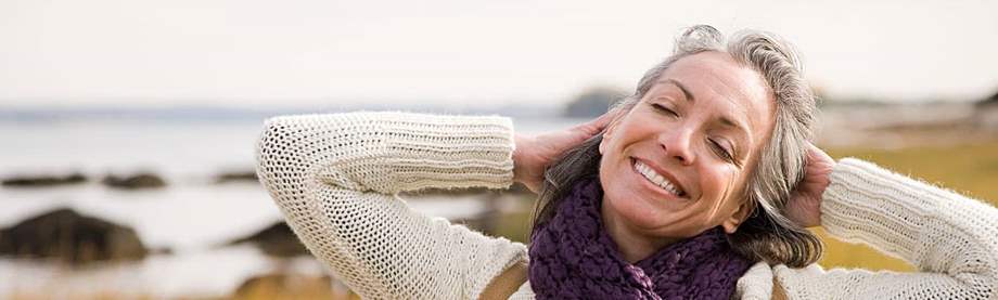 Woman stretching and smiling by the shore after considering her asset allocation in retirement