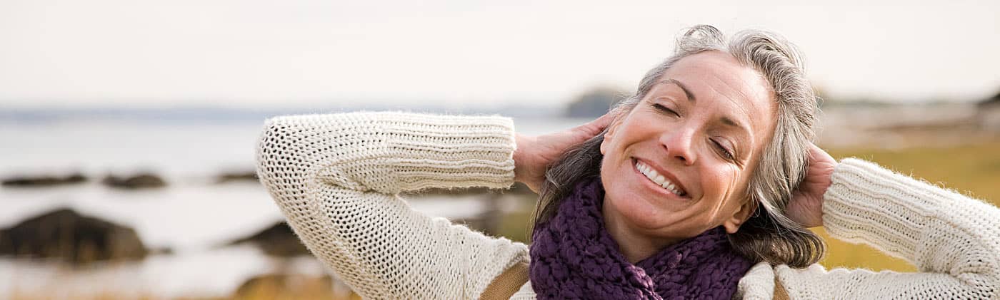 Woman stretching and smiling by the shore after considering her asset allocation in retirement 