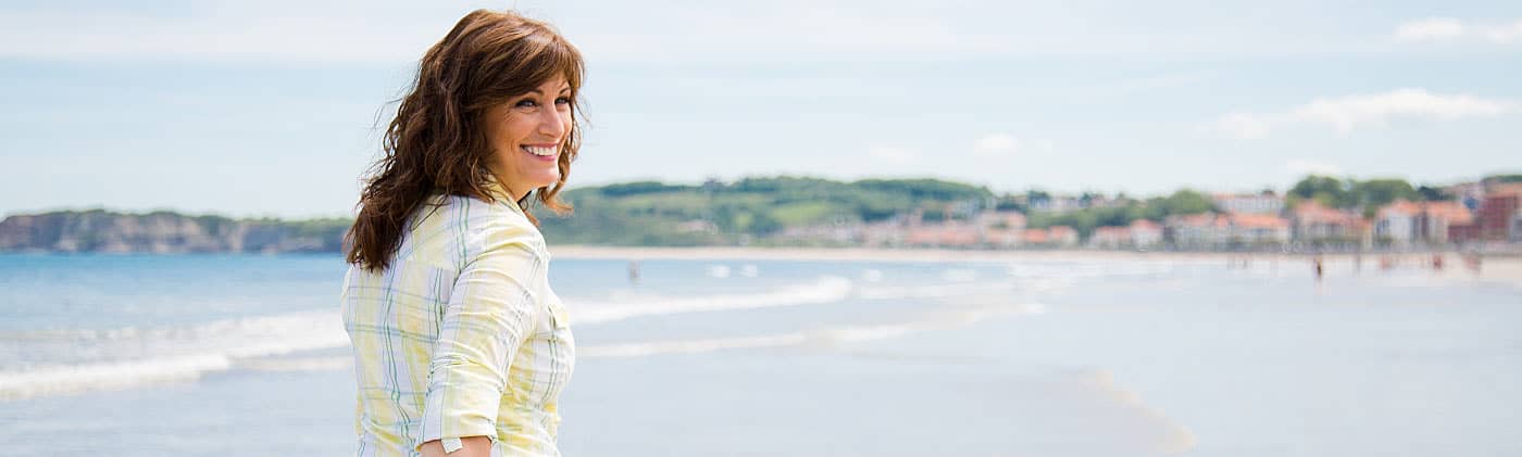 Woman walking on a beach and wondering how to improve your finances 
