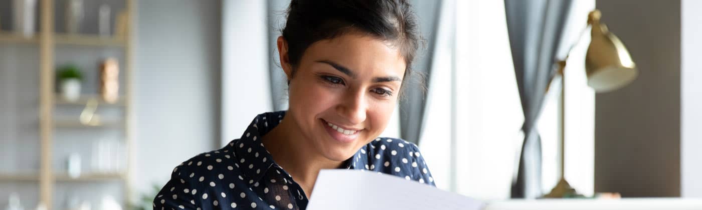 A woman looks at papers and a laptop while doing year-end tax planning