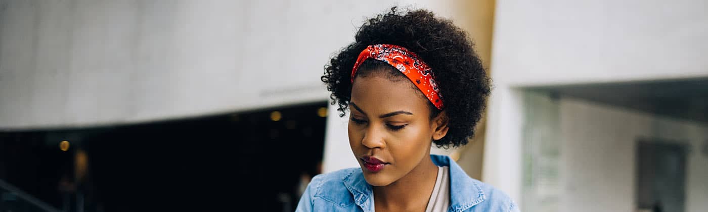 Younger African American woman researching ways to invest with little money 