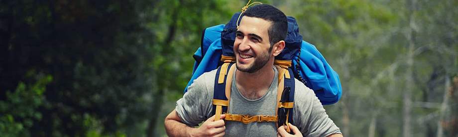 Young, happy hiker carrying a backpack up a hill and wondering if single people need life insurance 