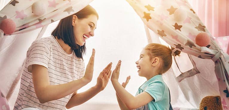 mom plays patty-cake game with her daughter inside bedroom tent and thinks about term life insurance