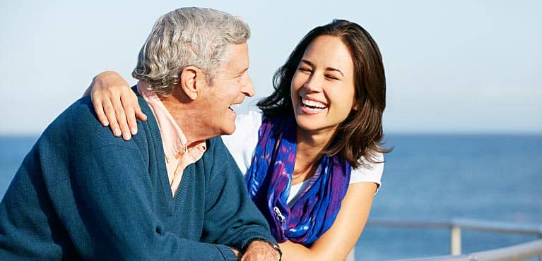 happy daughter embraces father near the ocean as they discuss average retirement savings by age