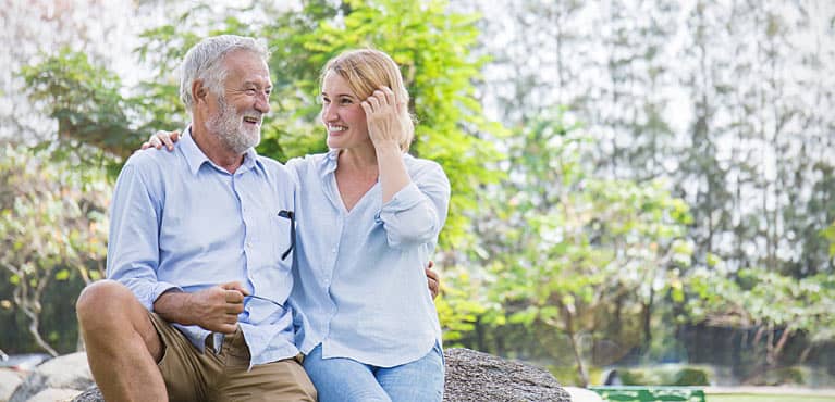 Retired couple smiling outside after discussing how they met their retirement goals 