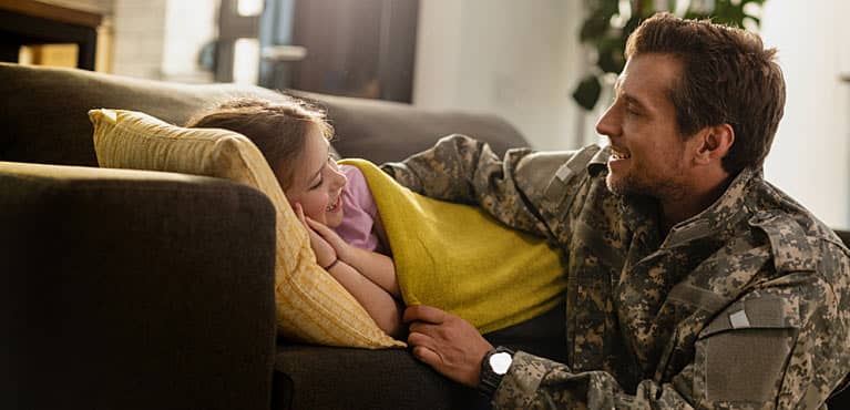 Veteran tucking his daughter in under a blanket on the couch after discussing active duty retirement 