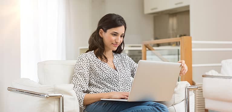 young woman conducts research on her laptop computer at home to determine her life insurance needs