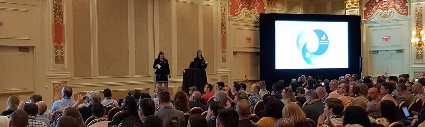 IT experts presenting on stage to large audience