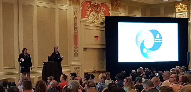 IT experts presenting on stage to large audience