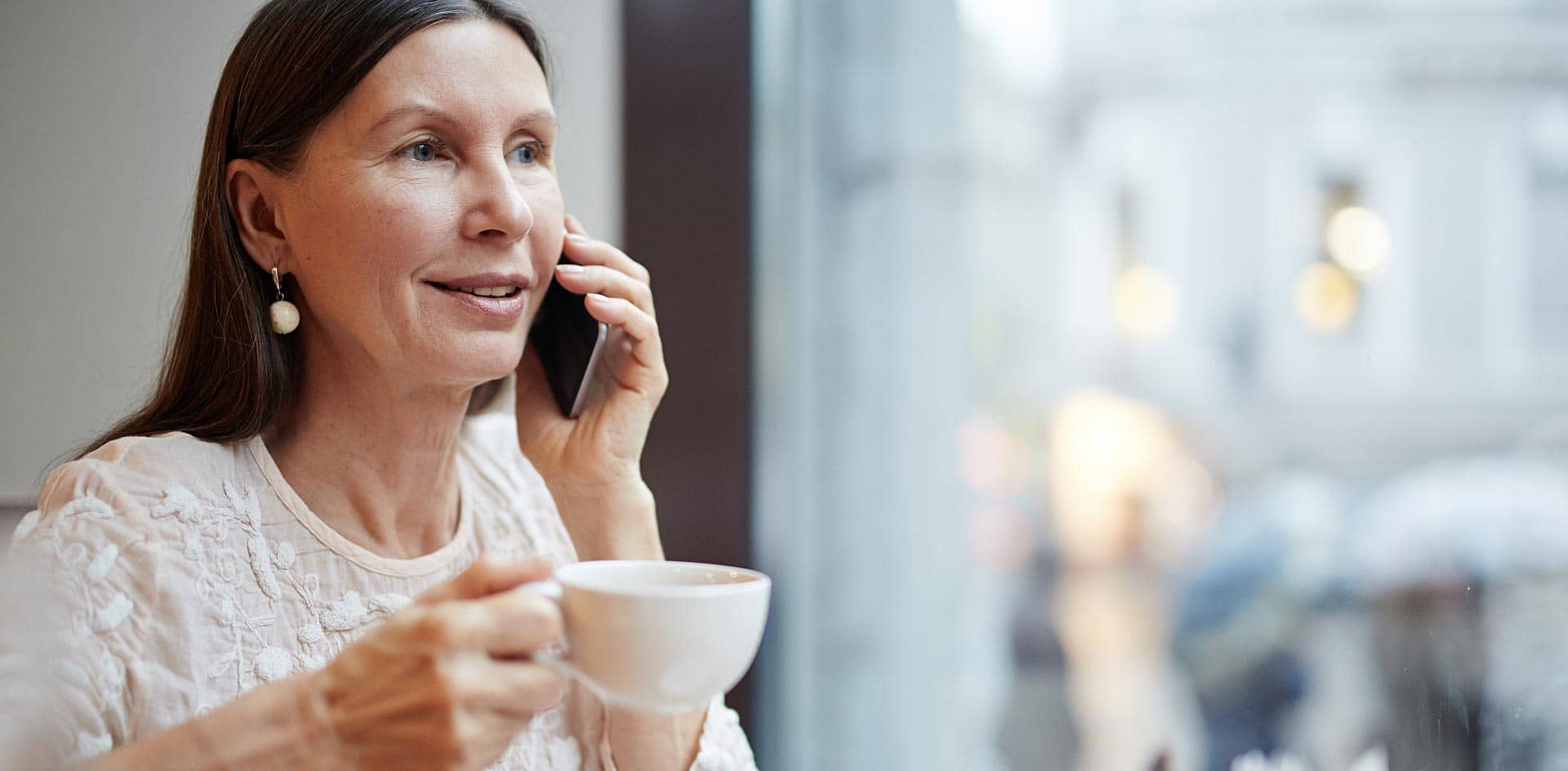 Woman talking to her husband on the phone at a cafe