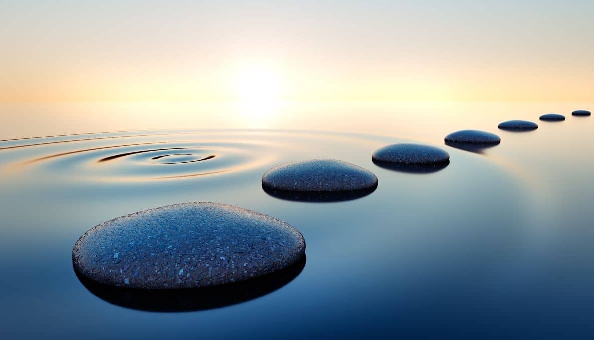 Stones in calm water with evening sun with horizon. Tranquil scenery.